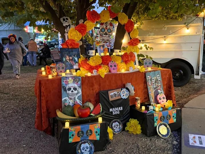 A community altar lined with candles and paper marigolds